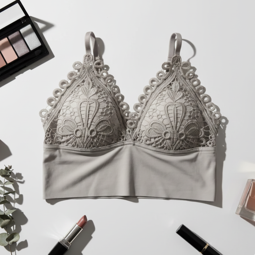 Gray lace bralette on a white background with makeup items around it.