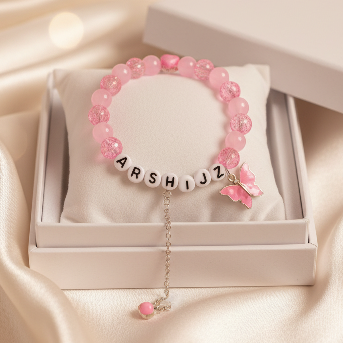 Pink beaded bracelet with letter beads in a white box on a satin surface