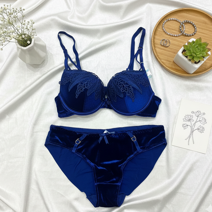 Blue bra and panties set on a white fabric background with decorative elements.