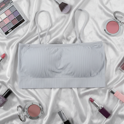 Gray bralette surrounded by makeup items on a white fabric background