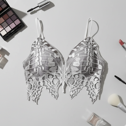 Butterfly-shaped earrings on a light gray background with makeup items.
