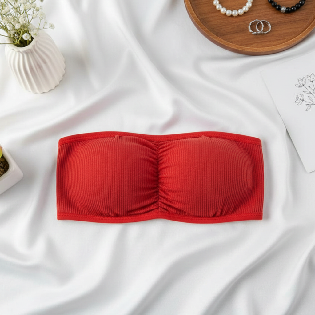 Red strapless bra on a white fabric background with decorative items.