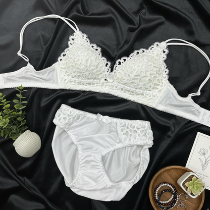 White lace bra and panties set on a dark fabric background with accessories.