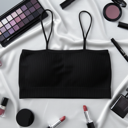 Black ribbed crop top surrounded by makeup items on a white fabric background
