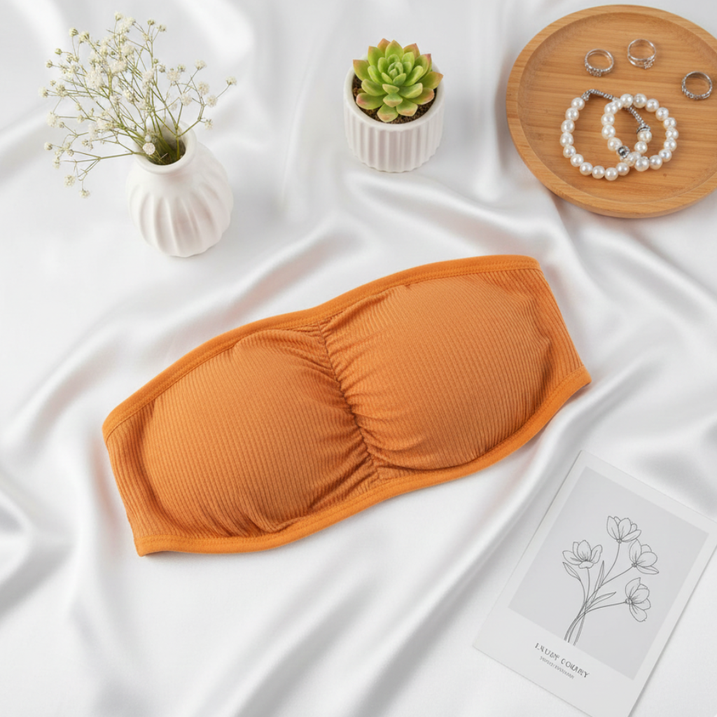 Orange bandeau top on a white fabric background with decorative items.
