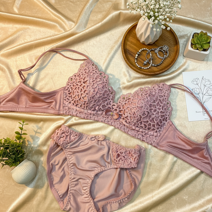 Pink lace lingerie set on a beige fabric background with decorative items.