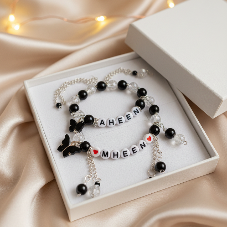 Black and white beaded bracelets with lettered charms in a box on a satin surface.