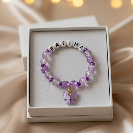 Purple beaded bracelet with 'FATIMA' on a white box against a soft background