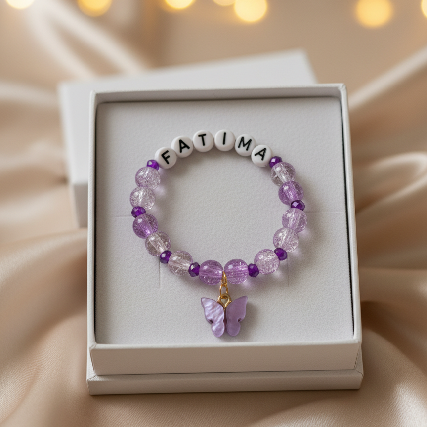 Purple beaded bracelet with 'FATIMA' on a white box against a soft, blurred background