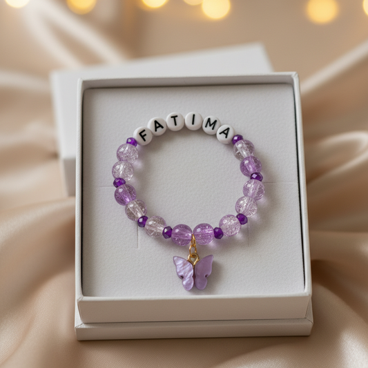 Purple beaded bracelet with 'FATIMA' on a white box against a soft, blurred background